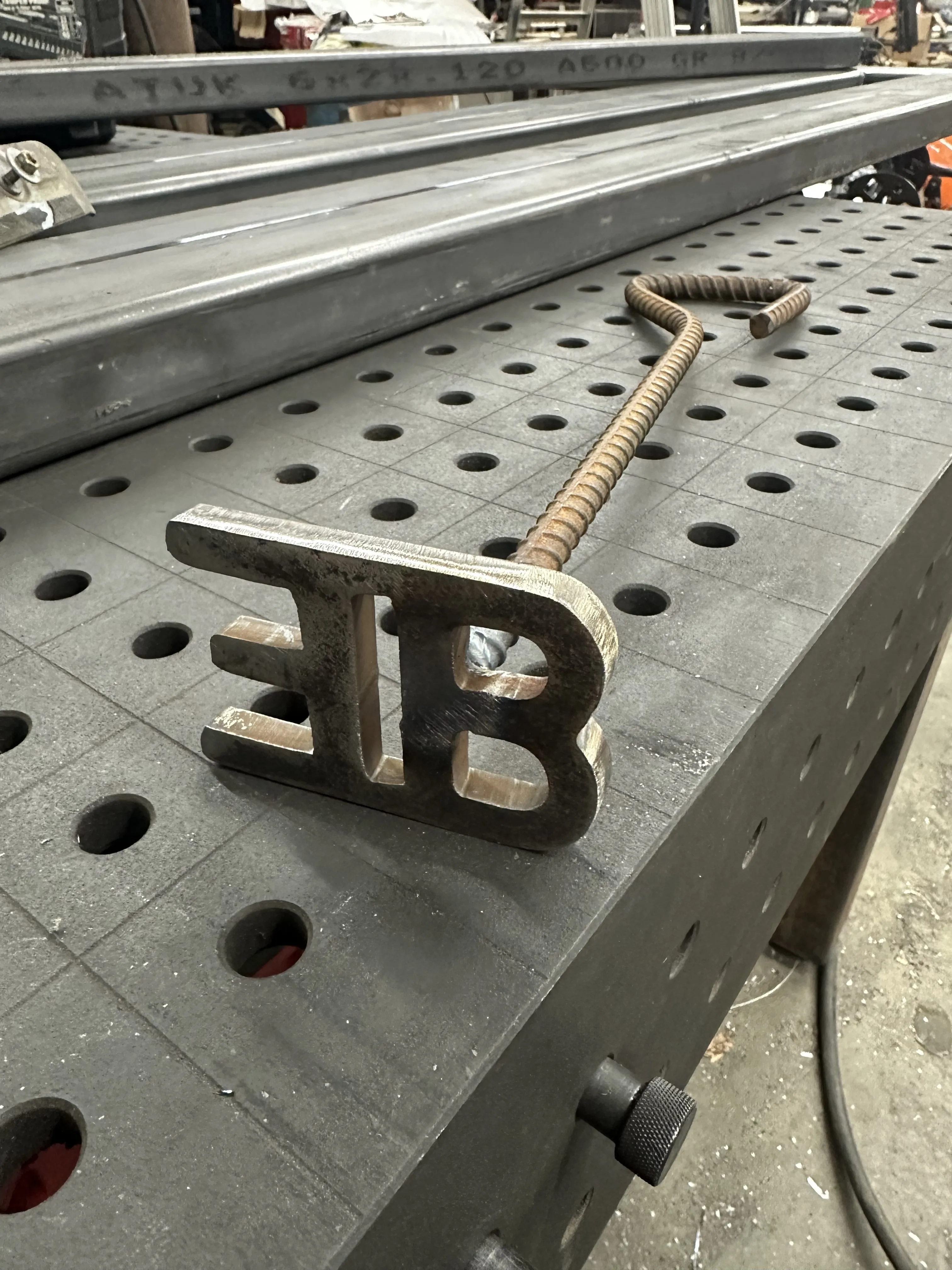 Custom formed metal branding element on a fabrication table